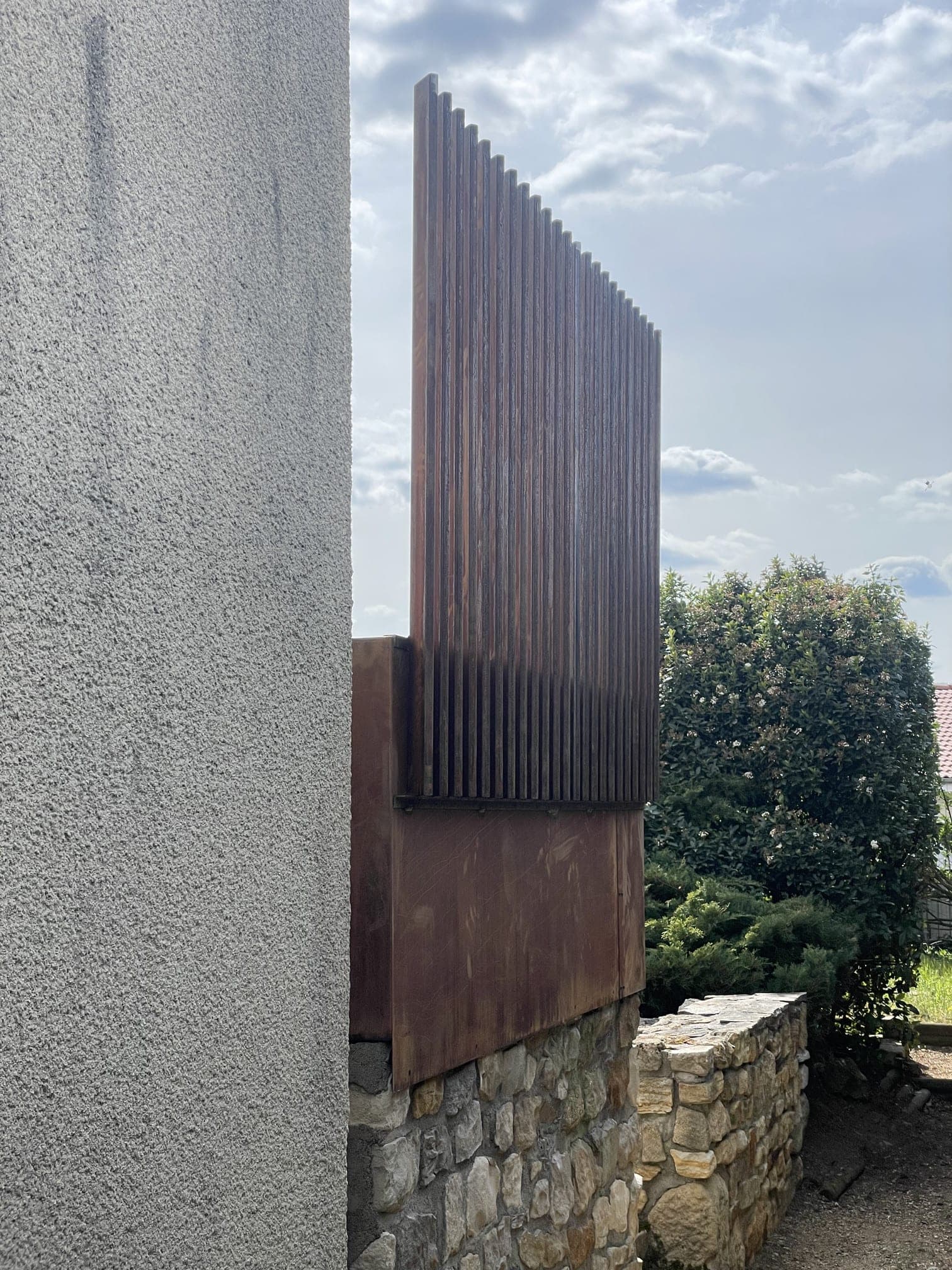 Vue latérale du claustra de lames verticales au-dessus du bac, à l’angle de la maison