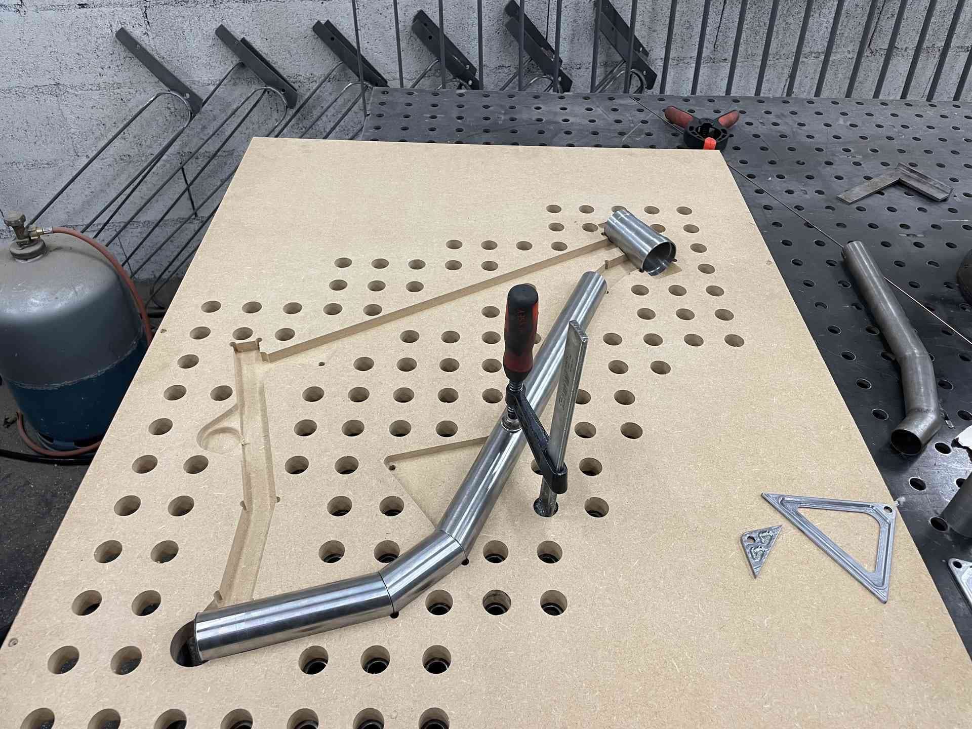 Gabarit en MDF sur la table de soudure perforée, tube cintré bridé en position