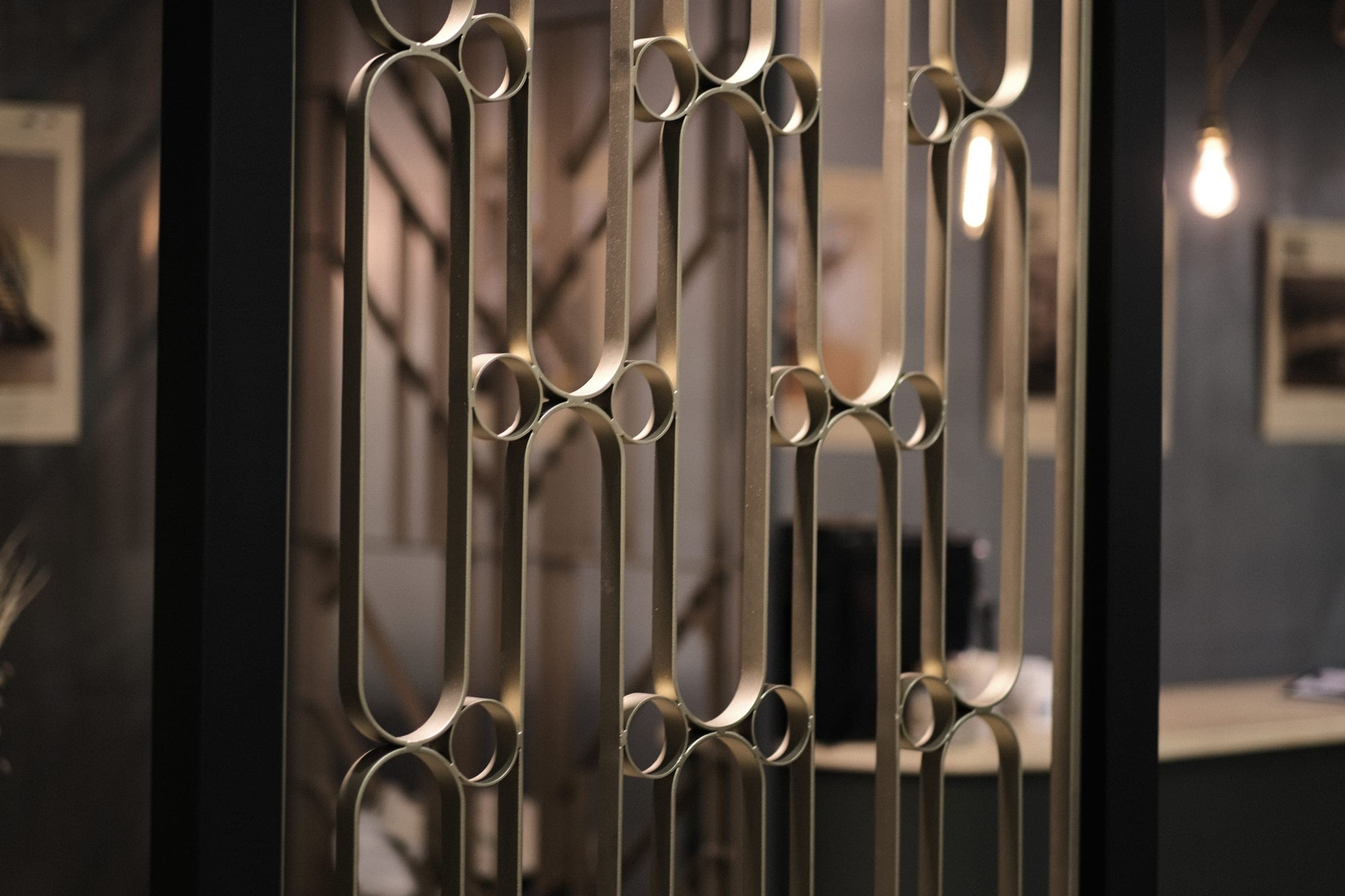 Détail du motif : ovales allongés en plat cintré reliés par de petits anneaux, finition bronze