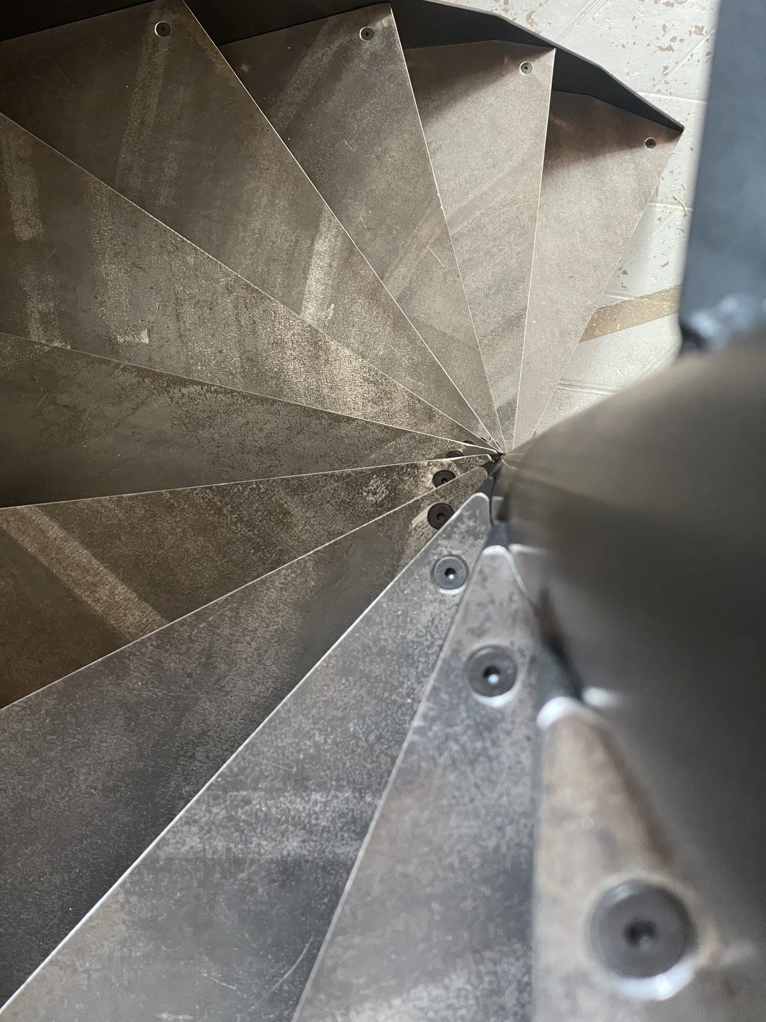 Détail des marches en acier brut vissées autour du fût central