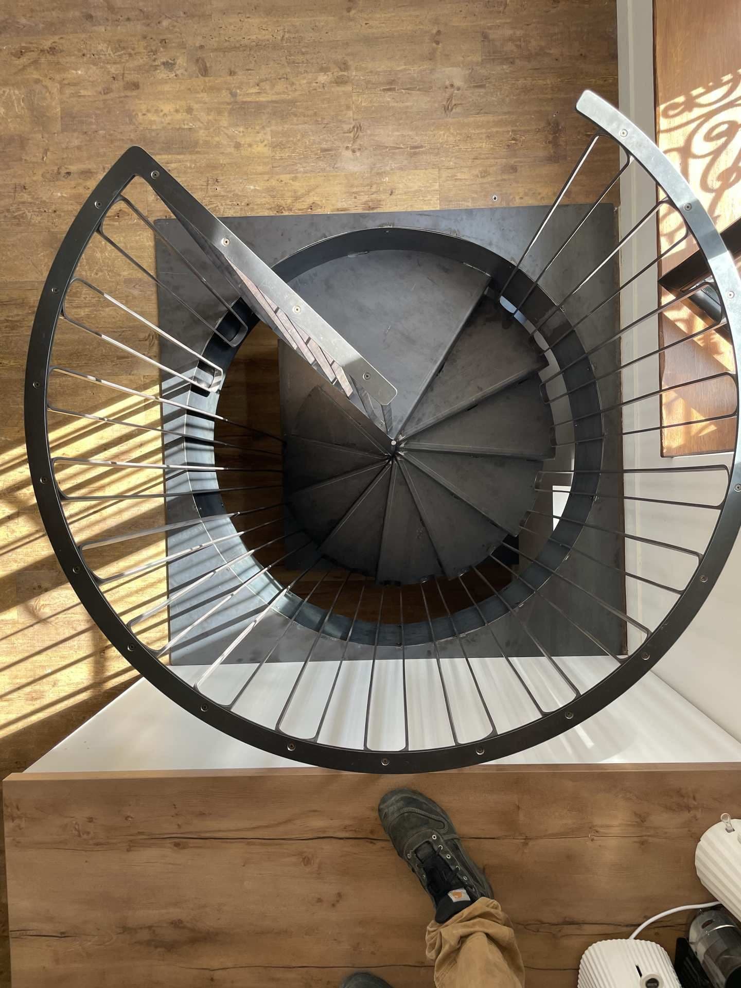 Vue plongeante sur l’escalier depuis l’étage, garde-corps d’arrivée en arc de cercle