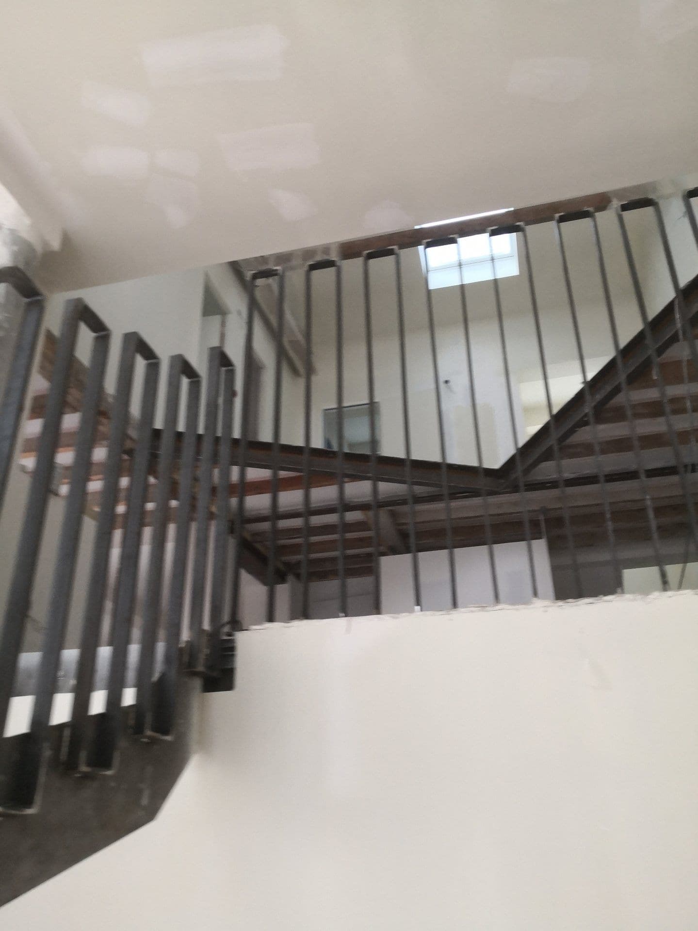 Contre-plongée sur le garde-corps du palier et les poutres du plancher haut