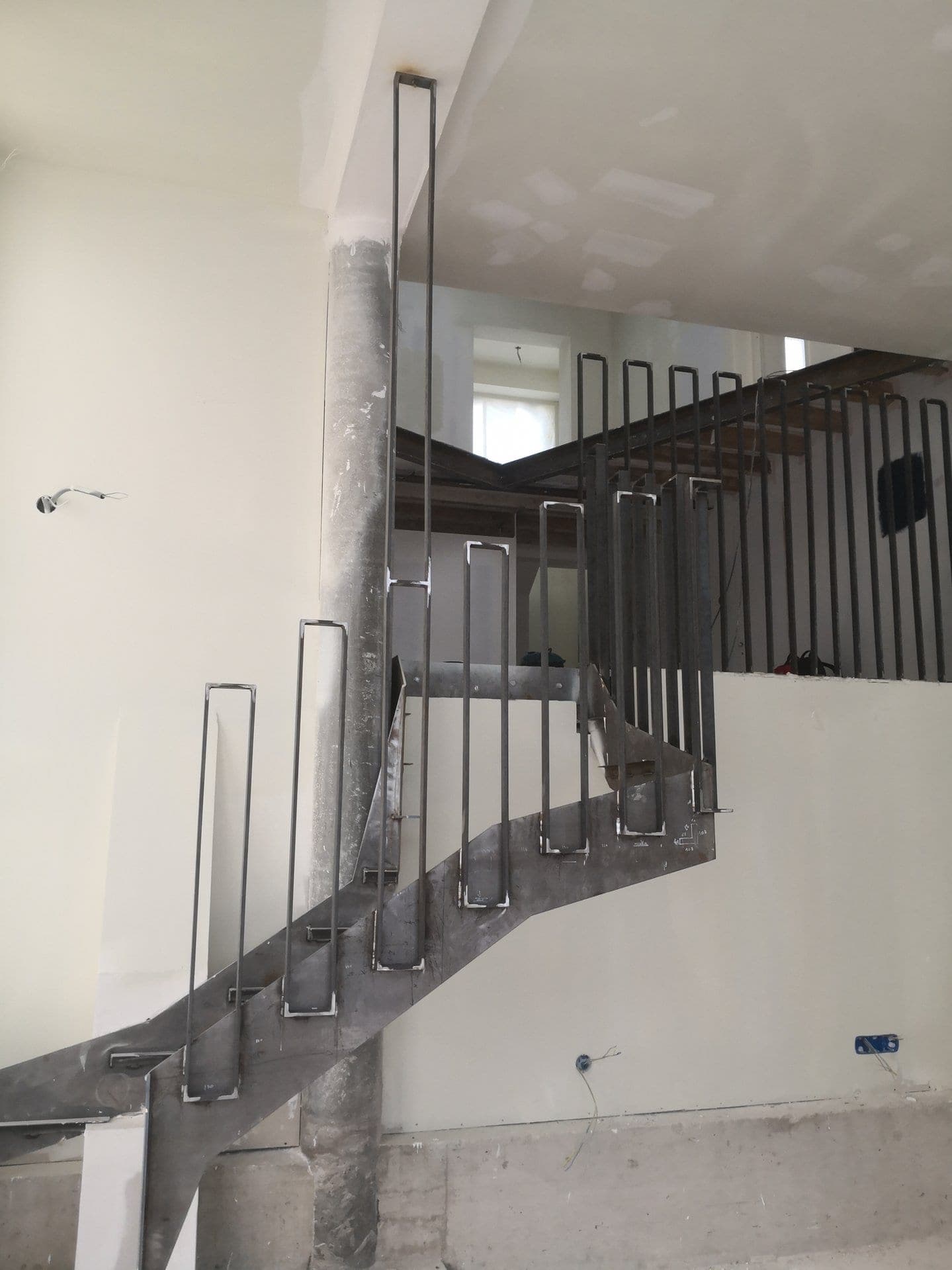 Escalier double quart tournant en acier brut, structure et garde-corps en épingle posés, sans les marches