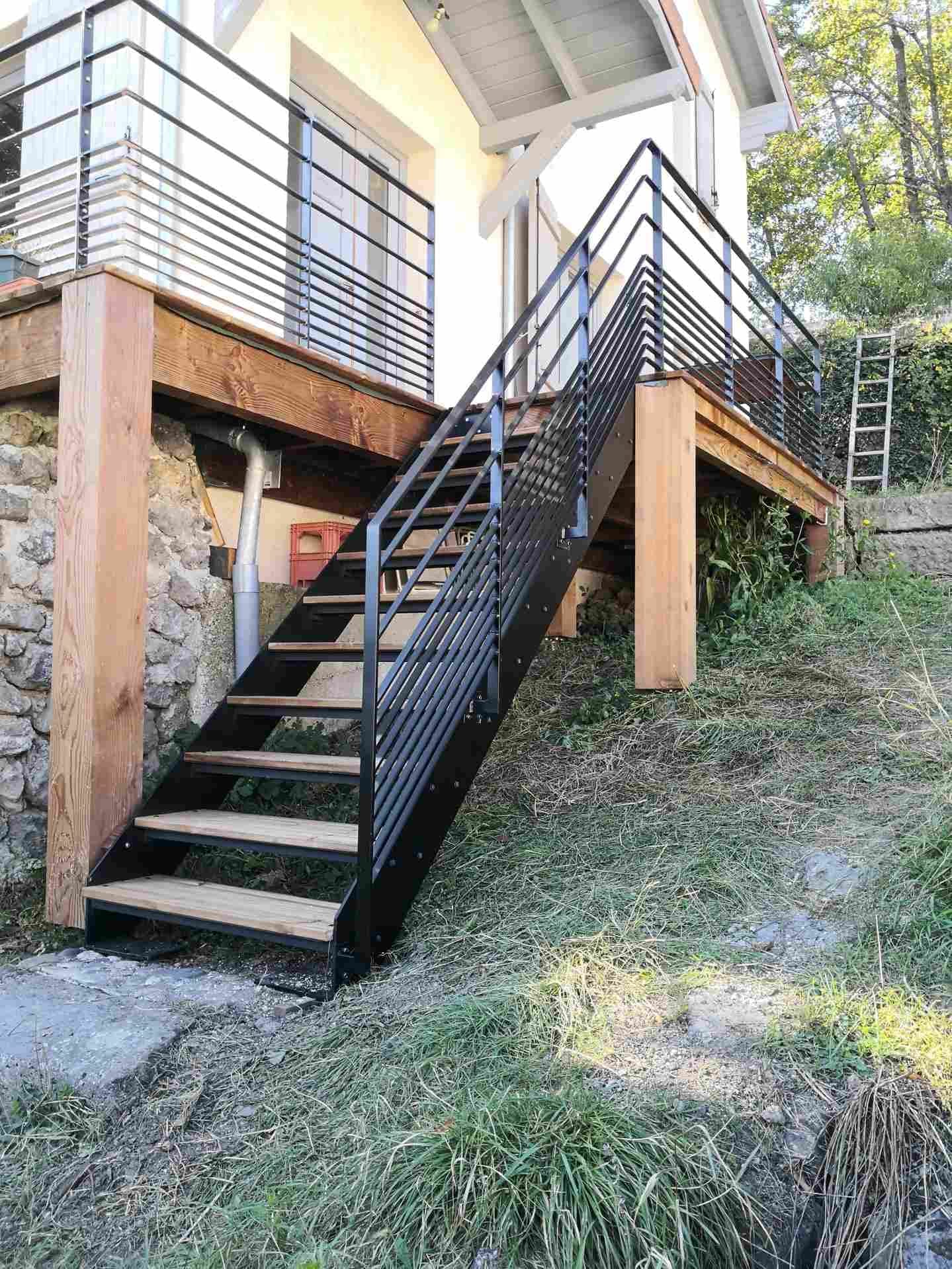 Escalier extérieur droit à double limon en acier noir et marches en bois, montant vers une terrasse surélevée