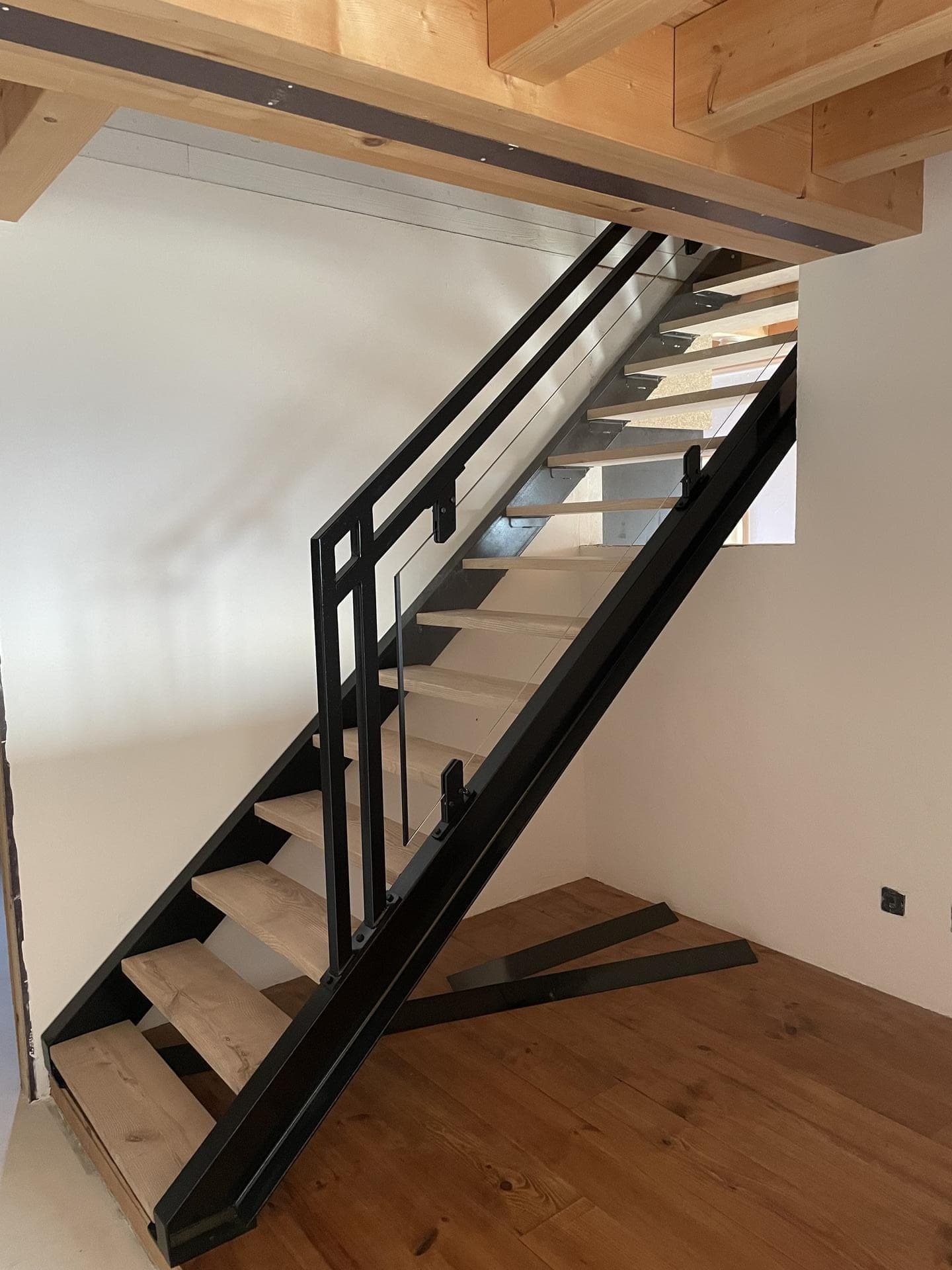 Vue d’ensemble de l’escalier droit : limons noirs, marches en chêne clair et garde-corps en acier et verre