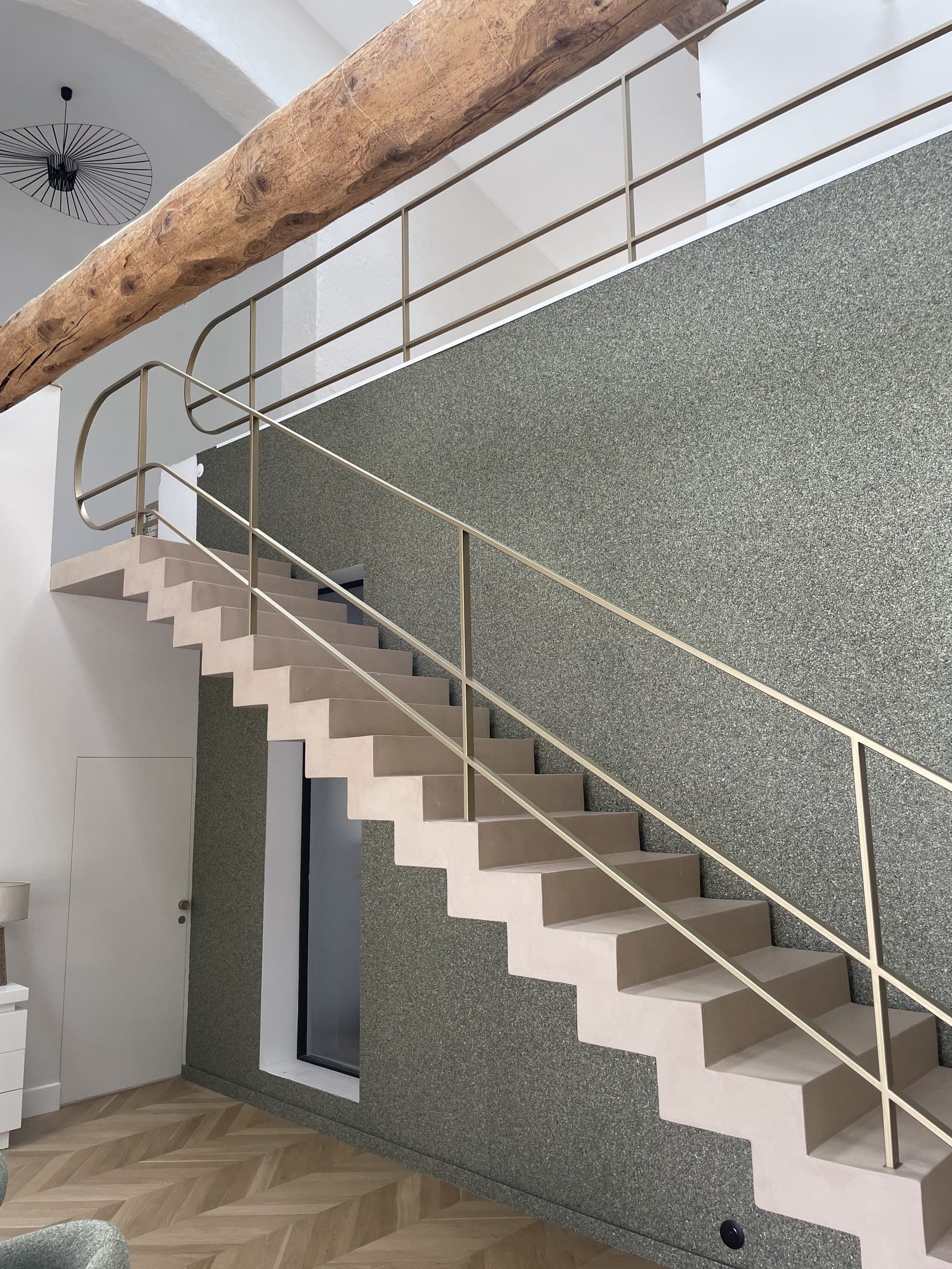 Garde-corps en acier peint or le long d’un escalier plein, avec retour en mezzanine, vu du rez-de-chaussée