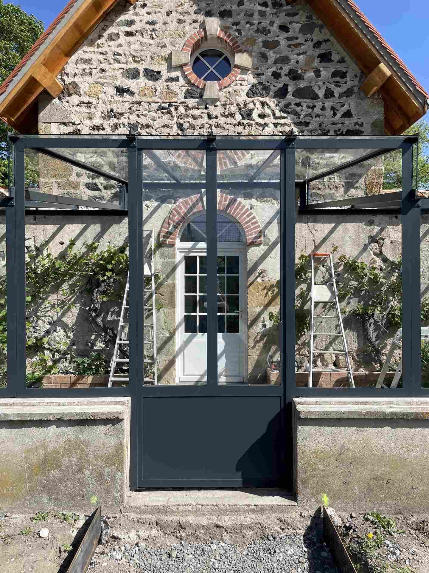 Porte de la serre à soubassement plein, dans l’axe de la porte cintrée du pignon en pierre