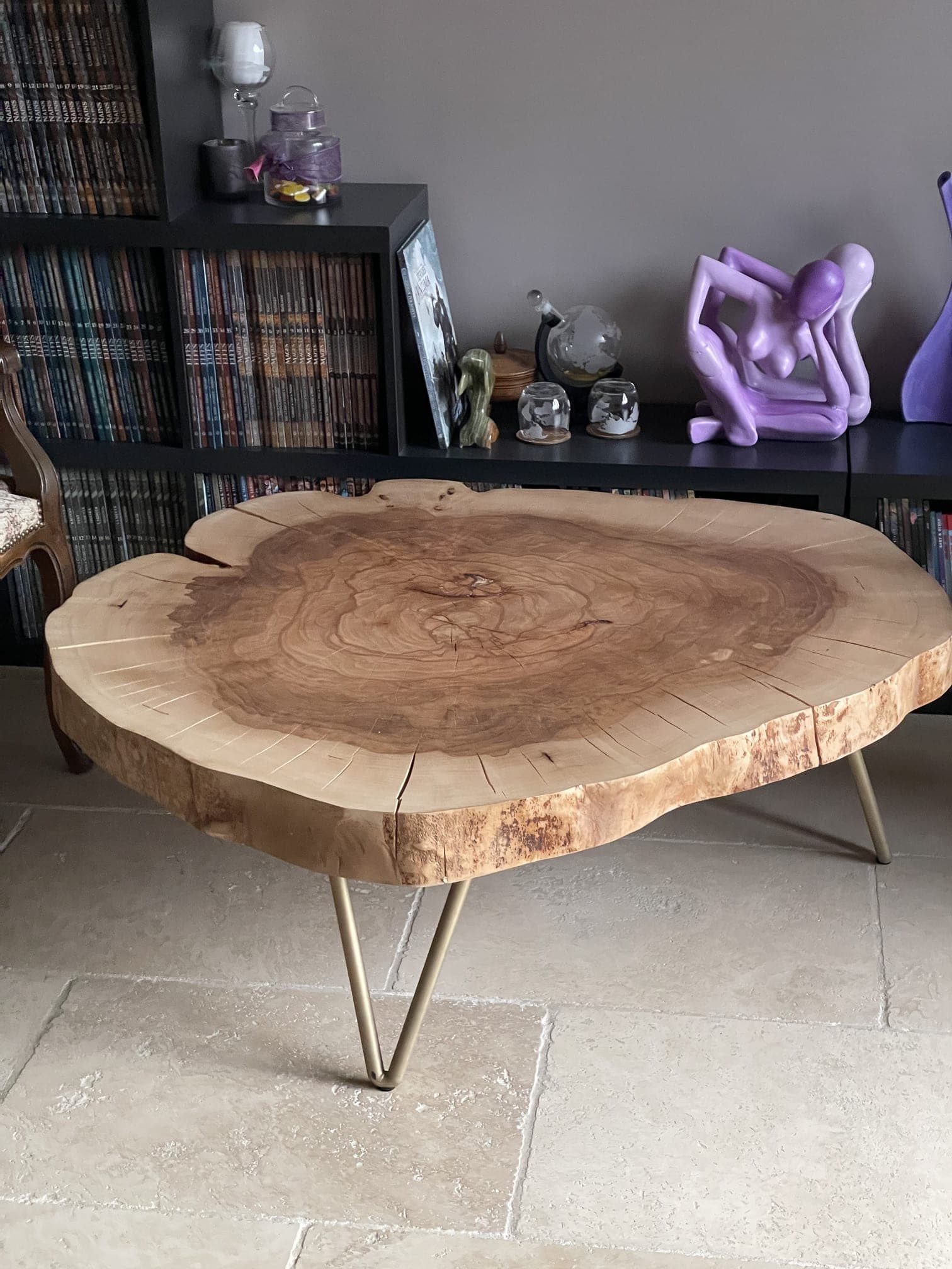 Table basse en tranche de hêtre sur pieds épingle dorés, vue de trois quarts dans un salon