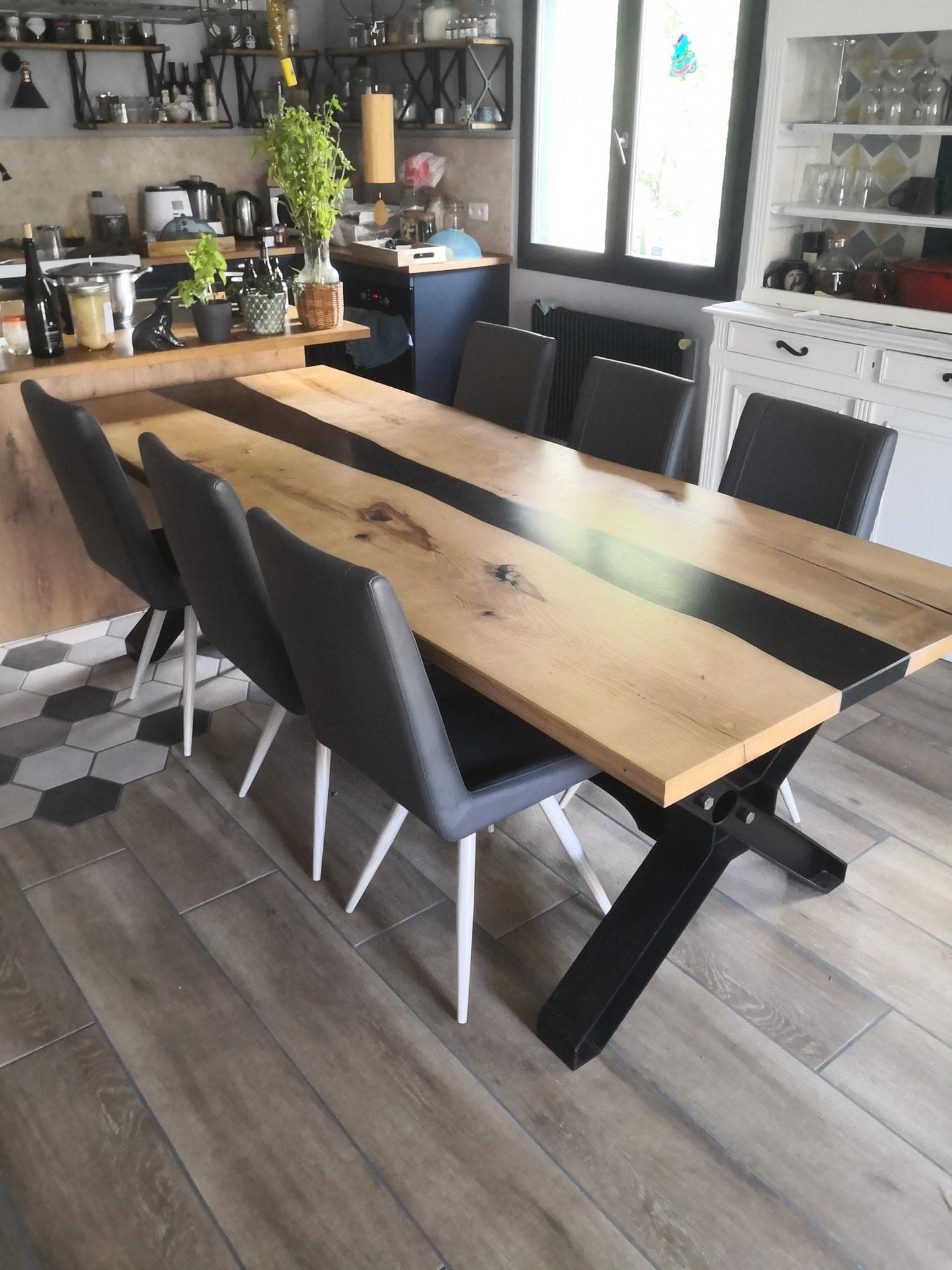 Table de repas en frêne à coulée d’époxy noire, pied en acier noir en X, dans une cuisine