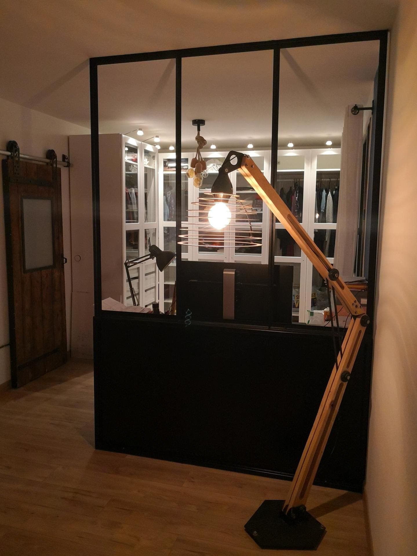 Verrière d’atelier en acier noir à trois travées vitrées sur soubassement plein, vue de face dans un intérieur
