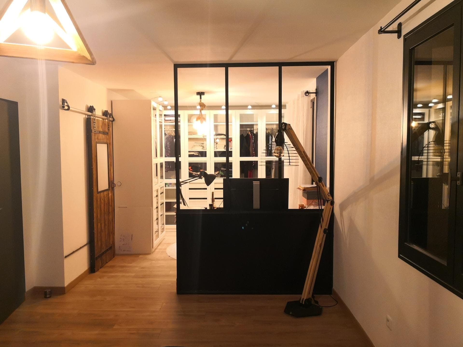 La verrière d’atelier vue depuis la pièce voisine, entre deux murs, devant le dressing éclairé
