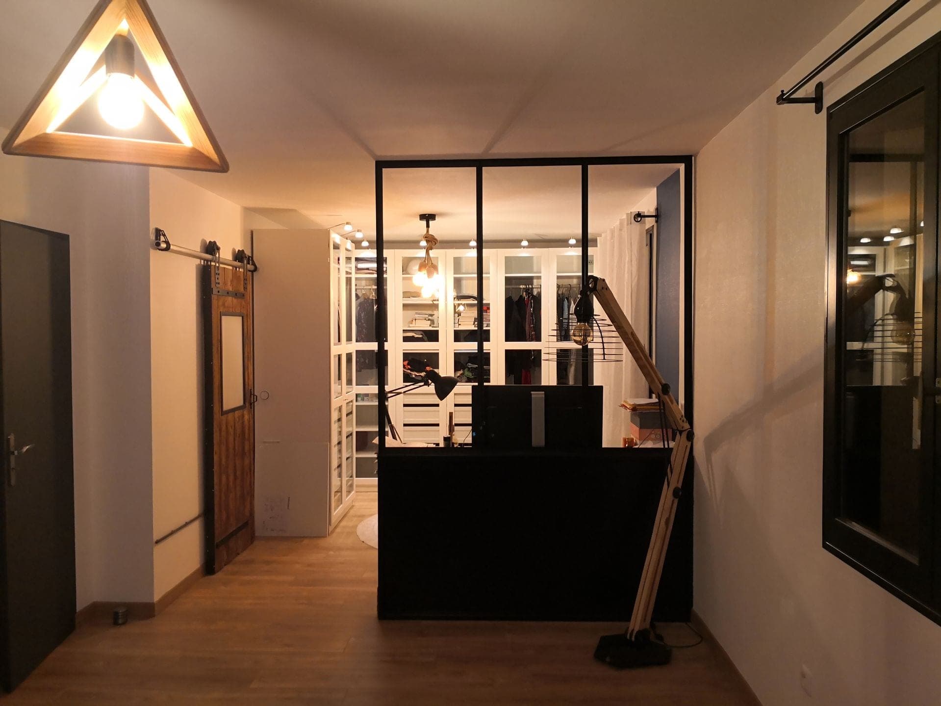 Vue d’ensemble de la pièce : la verrière noire ferme le coin bureau, porte coulissante en bois à gauche