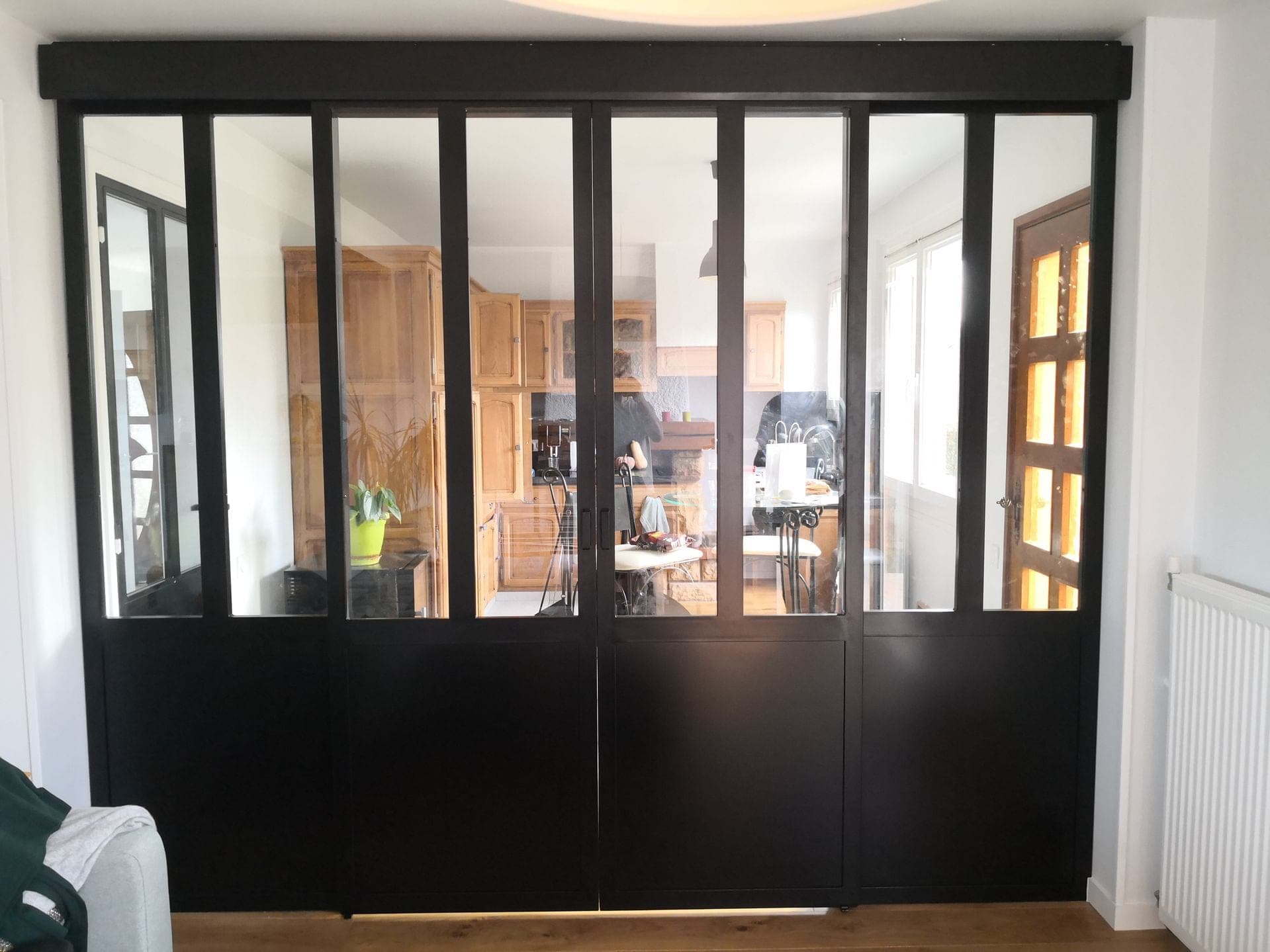 Verrière d’atelier noire vue de face depuis le salon, portes coulissantes fermées