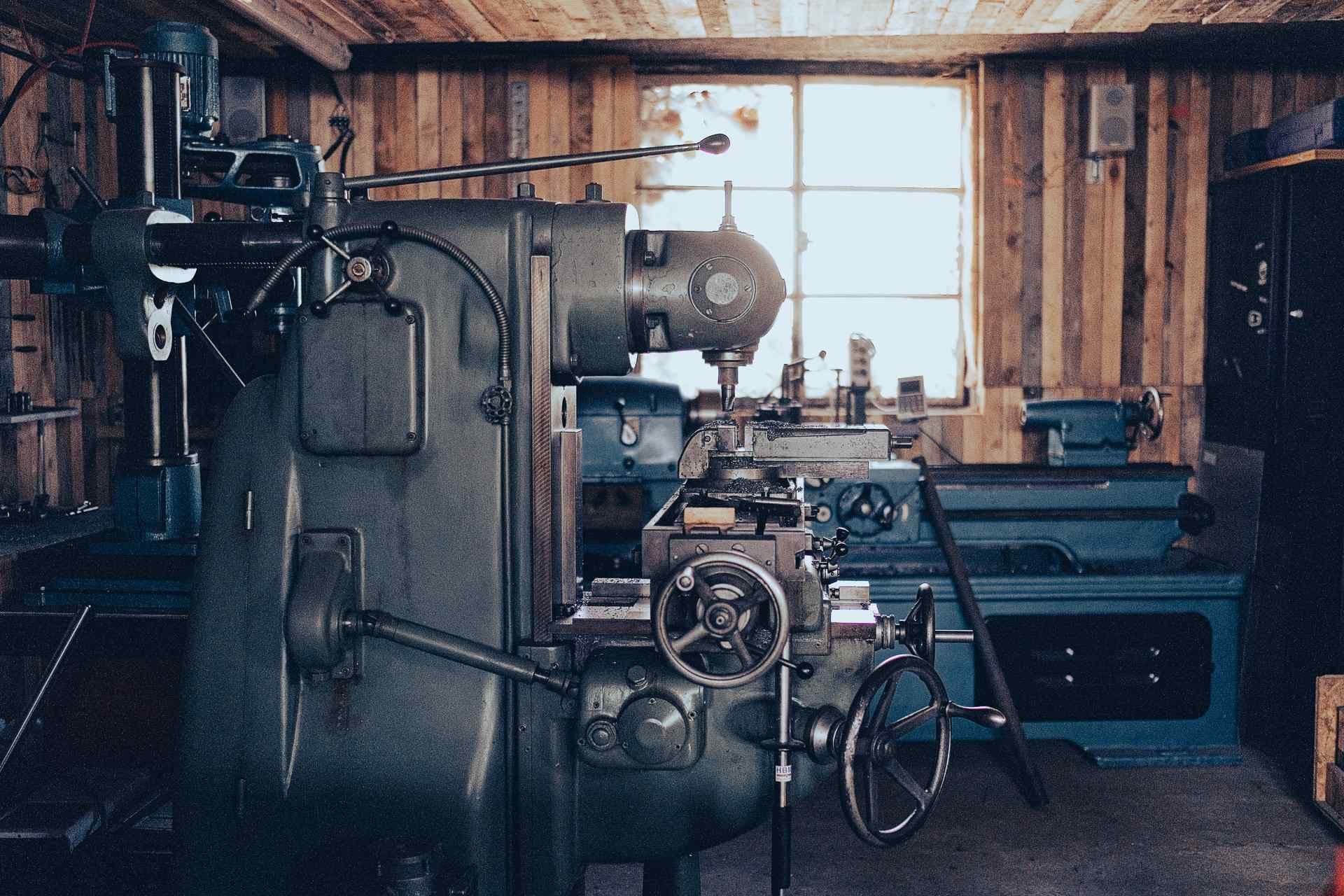 Salle des machines-outils : fraiseuse au premier plan, tour et perceuse à colonne en arrière-plan.