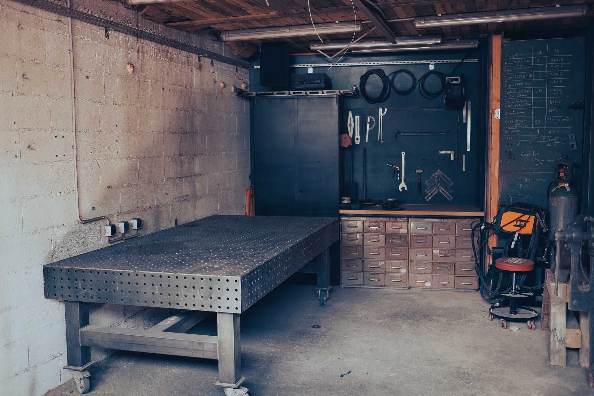 Espace soudure : table perforée sur roulettes, panneau d’outils, casiers à tiroirs et poste à souder.