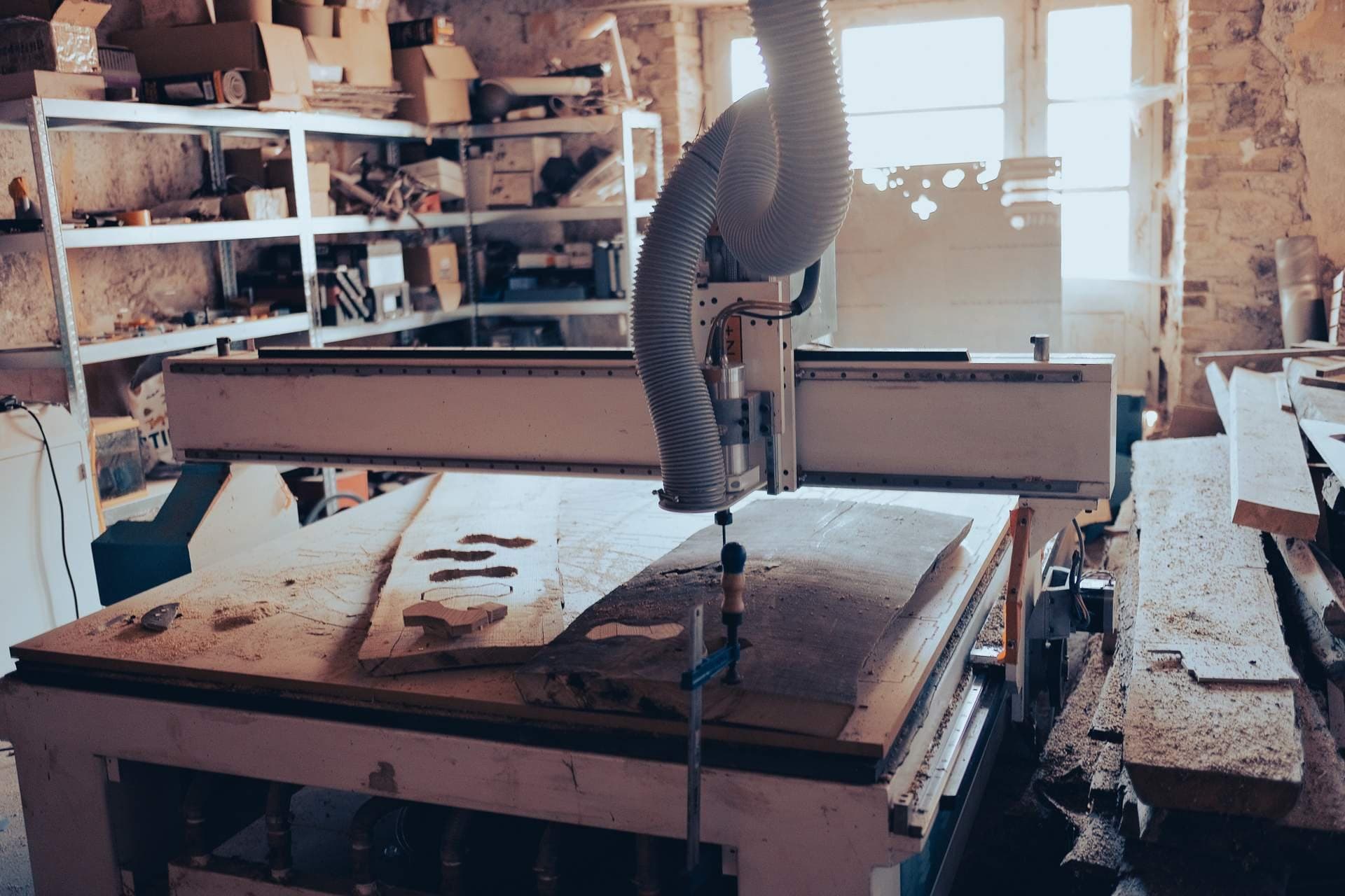 Fraiseuse numérique en cours d’usinage d’une planche de bois brut, avec aspiration des copeaux.